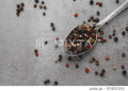 Spoon with mixed peppercorns on grey table, flat lay 95803391
