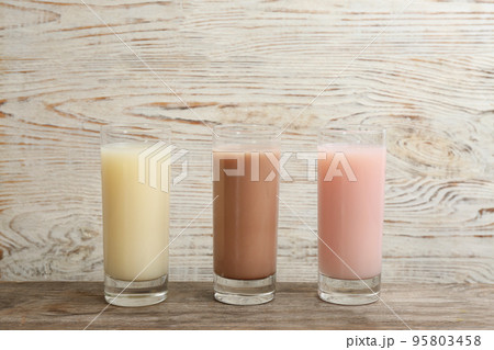 Different protein shakes in glasses on wooden table 95803458