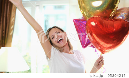 Happy beautiful woman with heart shaped air balloons Happy beautiful woman with heart shaped air balloons 95804215