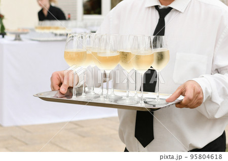 A waiter serving champagne at a wedding 95804618