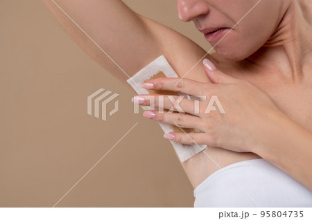 Young woman doing depilation in underarms area 95804735