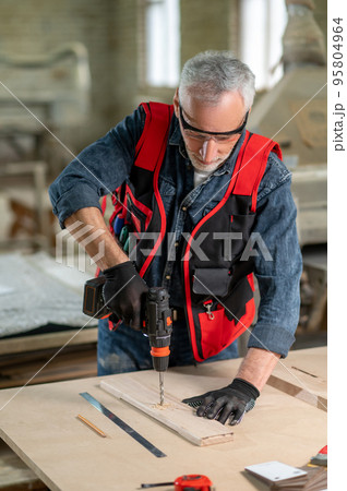 Craft person drlling wood in the workshop Craft person drlling wood in the workshop 95804964