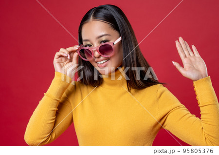 Joyful brunette posing for the camera against the red background 95805376