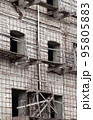 Brick wall of old destroyed house without windows with wooden broken scaffold 95805883