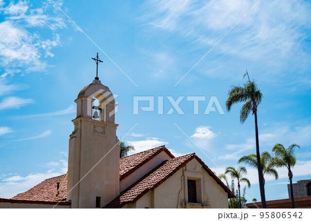 La Jolla Spanish mission style church bell tower with palm trees in San diego California. Religious symbolism of mexican culture La Jolla Spanish mission style church bell tower with palm trees in San diego California. Religious symbolism of mexican culture 95806542