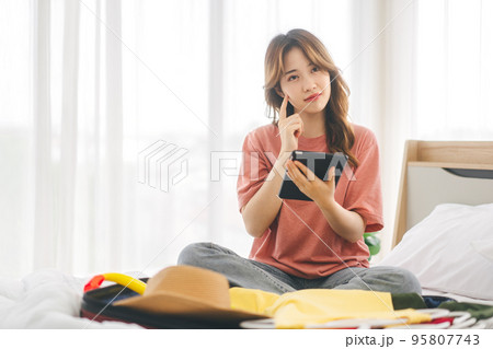 Portrait of young adult asian woman with travel luggage thinking about backpack trip at bedroom 95807743