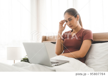 Young adult asian woman using laptop on bed for telemedicine mental health online therapy 95807764