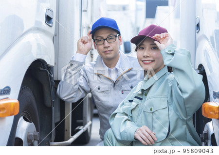 トラックのタイヤを点検する男女のドライバー 95809043