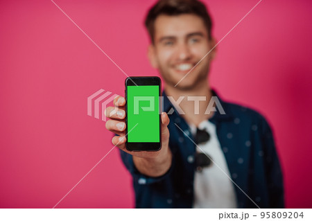 Portrait of a happy man using smartphone isolated over pink background. 95809204