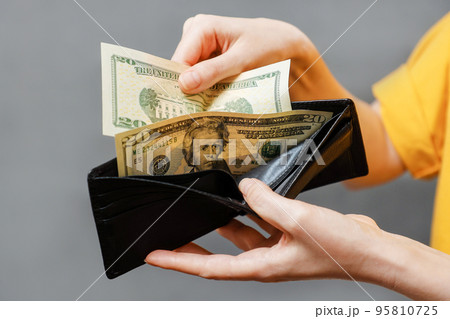 Savings. Woman's hands take out dollar bills from a leather black wallet. Close-up. The concept of shopping and payment Savings. Woman's hands take out dollar bills from a leather black wallet. Close-up. The concept of shopping and payment 95810725