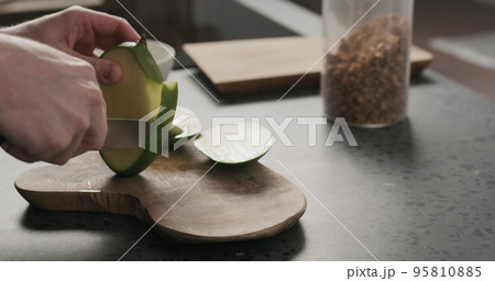 man cut green mango on olive wood board 95810885