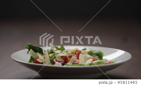 making salad pour dressing over in white bowl 95811465