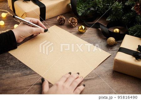 Closeup image of woman writing Christmas wishes on blank sheet Closeup image of woman writing Christmas wishes on blank sheet 95816490