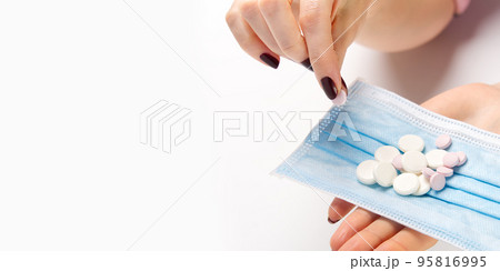 concept covid vaccine pills. COVID-19. Medical mask on a hand with white background. Medicine pills or Vaccine against the virus. concept covid vaccine pills. COVID-19. Medical mask on a hand with white background. Medicine pills or Vaccine against the virus. 95816995