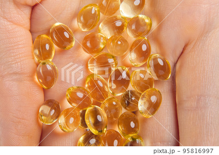 Women hand with gel capsules of D Vitamin . Vitamin Omega-3 fish oil in capsules. hand holding gelcap or softgel transparent capsule pills Women hand with gel capsules of D Vitamin . Vitamin Omega-3 fish oil in capsules. hand holding gelcap or softgel transparent capsule pills 95816997