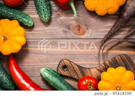 Frame of fresh vegetables - squash, cucumbers, tomatoes, zucchini, peppers on a wooden table. Top view Frame of fresh vegetables - squash, cucumbers, tomatoes, zucchini, peppers on a wooden table. Top view 95818506