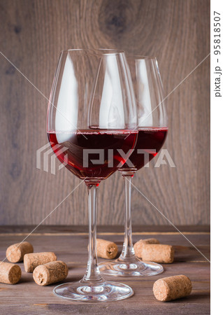 Two glasses with red wine and cork on a wooden table Two glasses with red wine and cork on a wooden table 95818507