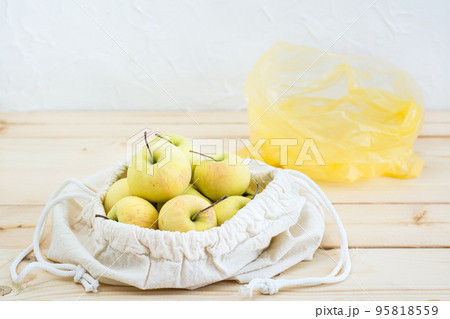 Canvas bag with ties with apples and a plastic bag on a natural wooden background. Zero Waste Concept Canvas bag with ties with apples and a plastic bag on a natural wooden background. Zero Waste Concept 95818559