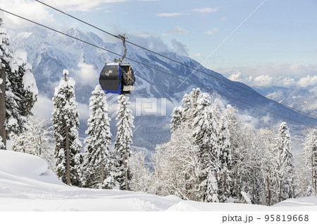 New modern spacious big cabin ski lift gondola against snowcapped forest tree and mountain peaks covered in snow landscape in luxury winter alpine resort. Winter leisure sports, recreation and travel New modern spacious big cabin ski lift gondola against snowcapped forest tree and mountain peaks covered in snow landscape in luxury winter alpine resort. Winter leisure sports, recreation and travel 95819668