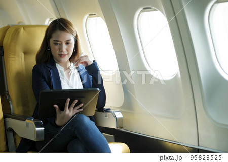 Business woman working on tablet while sitting in airplane. 95823525