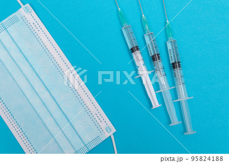 Syringe with Medical Mask on Blue Table - Flat Lay 95824188