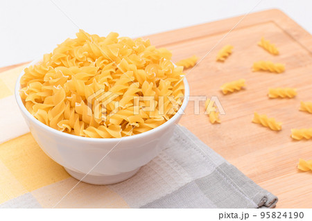 Uncooked Fusilli Pasta in White Bowl on Wooden Board Uncooked Fusilli Pasta in White Bowl on Wooden Board 95824190