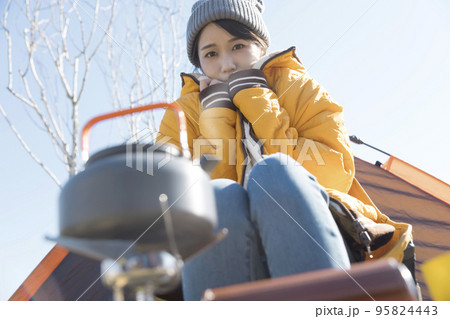 冬キャンイメージ 冬キャンプで防寒しながらお湯が沸くのを待つ若い女性 冬キャンイメージ 冬キャンプで防寒しながらお湯が沸くのを待つ若い女性 95824443