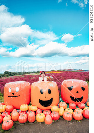仮装してハロウィンのかぼちゃと一緒に写る女性 95824816