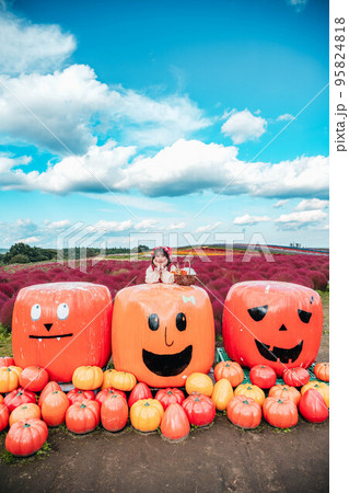 仮装してハロウィンのかぼちゃと一緒に写る女性 95824818
