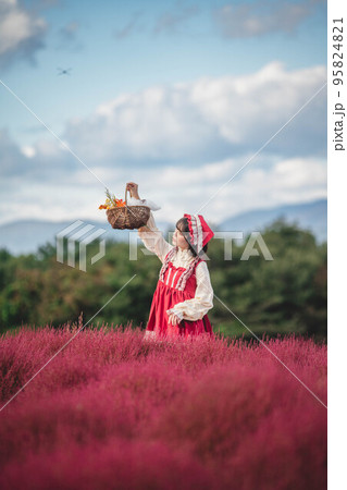 カラフルな花園にいる赤ずきんの仮装をした女性 95824821