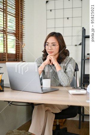 Professional and thoughtful Asian businesswoman concentrating working on her tasks in office 95825021