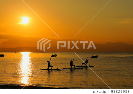 夕暮れの逗子海岸、SUPヨガを楽しむ女性たちのシルエット 夕暮れの逗子海岸、SUPヨガを楽しむ女性たちのシルエット 95825933