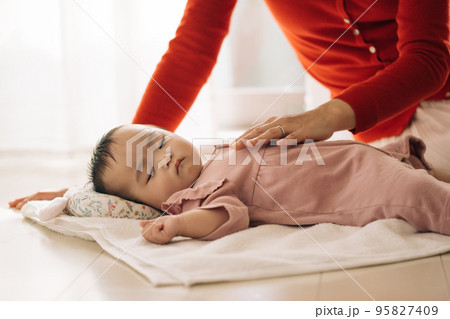 タオルの上で横になる赤ちゃんと、添い寝するママ 95827409