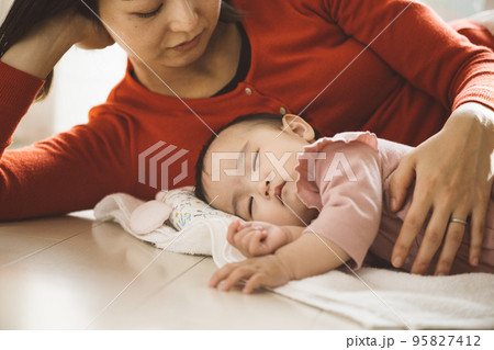 タオルの上で横になる赤ちゃんと、添い寝するママ 95827412