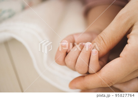 ママの親指を握る赤ちゃんの手 95827764