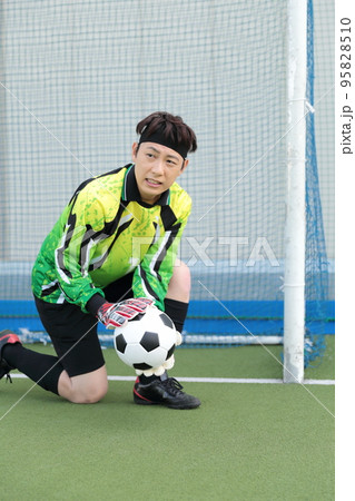 サッカーボールをキャッチするゴールキーパーの男性 95828510