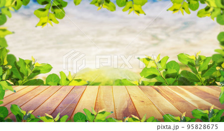 Brown blank wooden table top with spring green leaves with the mountain landscape. Spring design with pine forest and empty display. 95828675