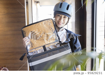 フードデリバリー 商品を受け取りに来て保冷バッグを開ける女性配送員 フードデリバリー 商品を受け取りに来て保冷バッグを開ける女性配送員 95829231