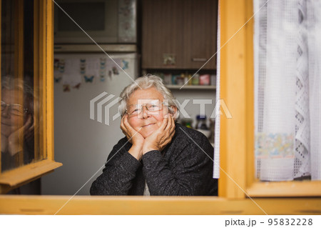 Portrait of lovely senior woman looking outside of the window, carefree old age 95832228