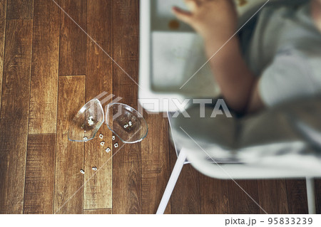 A small baby on a high chair dropped a cup of noodle soup on the wooden floor. The transparent plate is divided into two parts. Noodles in the form of figures. The table is dirty. High quality photo A small baby on a high chair dropped a cup of noodle soup on the wooden floor. The transparent plate is divided into two parts. Noodles in the form of figures. The table is dirty. High quality photo 95833239