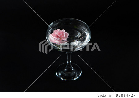 Glass with water and white, pink flowers on a black isolated background. Advertisement for perfumes and creams. High quality photo. 95834727