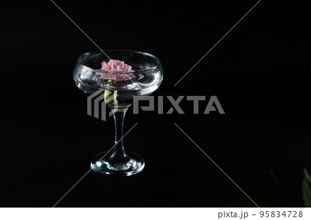 Glass with water and white, pink flowers on a black isolated background. Advertisement for perfumes and creams. High quality photo. Glass with water and white, pink flowers on a black isolated background. Advertisement for perfumes and creams. High quality photo. 95834728
