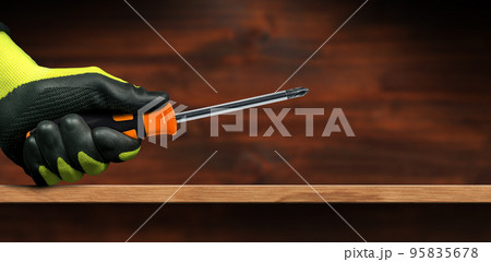 Manual Worker with Protective Work Gloves Holding a Phillips Head Screwdriver Manual Worker with Protective Work Gloves Holding a Phillips Head Screwdriver 95835678