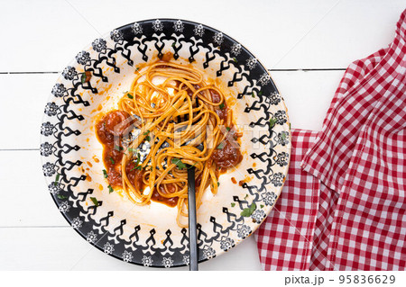 Top view of a plate of Italian spaghetti with sausage and tomato sauce with leftover pasta and sauce. 95836629