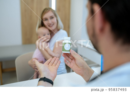 Pediatrician after check up prescribing vitamins to a young mom with a baby Pediatrician after check up prescribing vitamins to a young mom with a baby 95837493