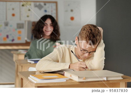 Selective focus on clever and diligent schoolboy making notes in copybook 95837830