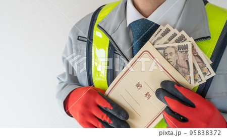 給料袋を持つ安全ベスト着用の作業服男性 95838372