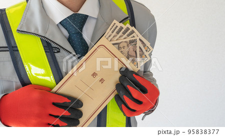 給料袋を持つ安全ベスト着用の作業服男性 95838377