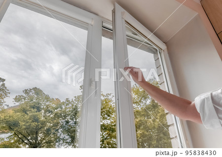 woman hand open pvc window with double glazing. Room ventilation concept 95838430
