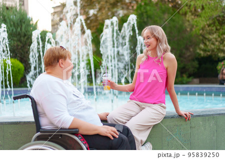 Young daughter taking care of her mother with disability sitting in wheelchair 95839250
